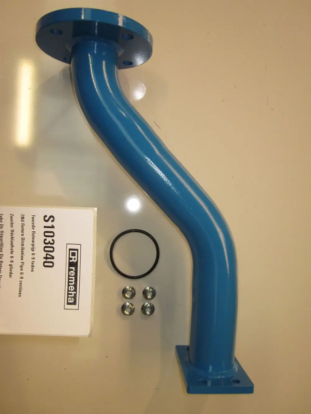 Blaues Rohr mit Flansch und gebogenem Design, dazu eine Gummidichtung und drei Schrauben, produziert von Remeha.